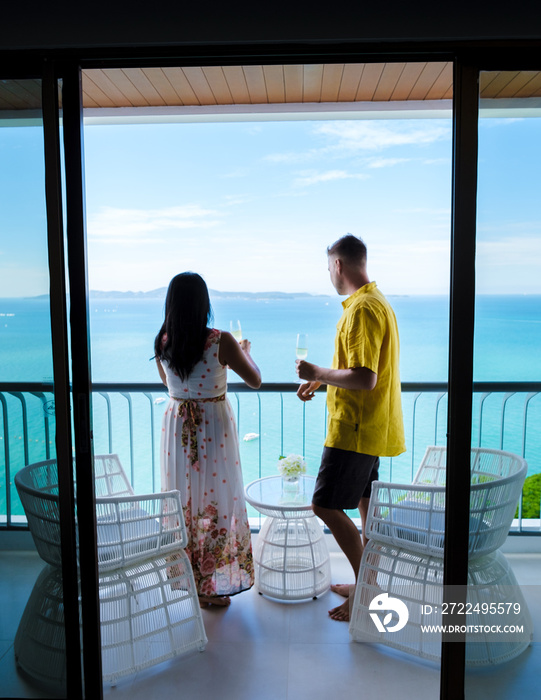 A couple of men and women drinking cocktails on the balcony of a hotel in Pattaya Thailand at sunset.