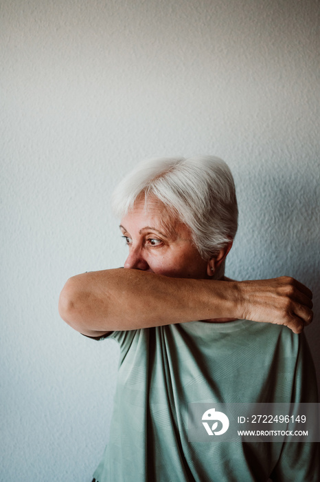 Senior woman coughing into elbow