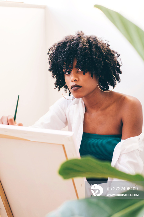 Beautiful black woman artist painting on canvas at home