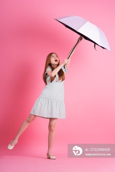 Young Asian woman holding umbrella on pink background