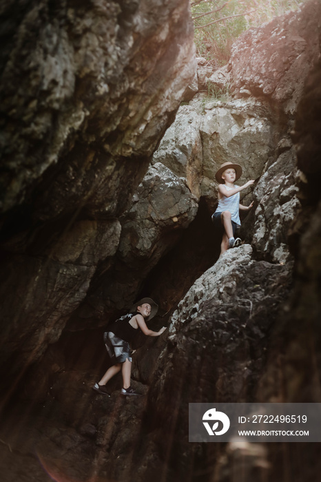 Moody image of young boys exploring cave by the beach at Coral Beach near Shute Harbour in the Whitsundays, Queensland Australia