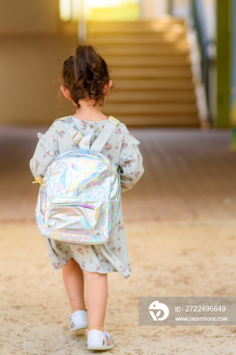 Happy kid back to school. Little girl with backpack go to elementary school. Child of primary school.Back view of pupil going to school for the first time.