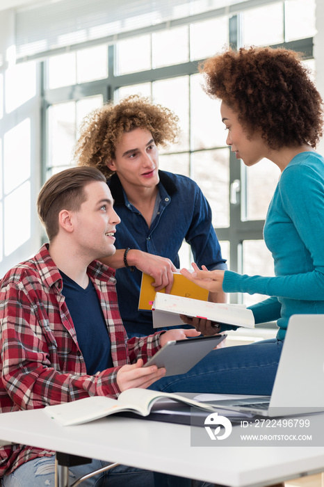 Three involved students sharing ideas and opinions about different topics and new information learned during courses at the university