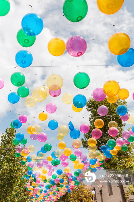 The street with cafes and bistros is decorated with colorful balloons