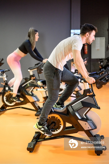 Man cycling on a modern fitness bicycle during group spinning class at the gym. High quality photo