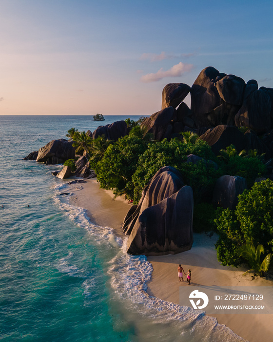 Anse Source d’Argent beach, La Digue Island, Seyshelles, Drone aerial view of La Digue Seychelles bird eye view.of tropical Island, couple men and woman walking at the beach during sunset at a luxury