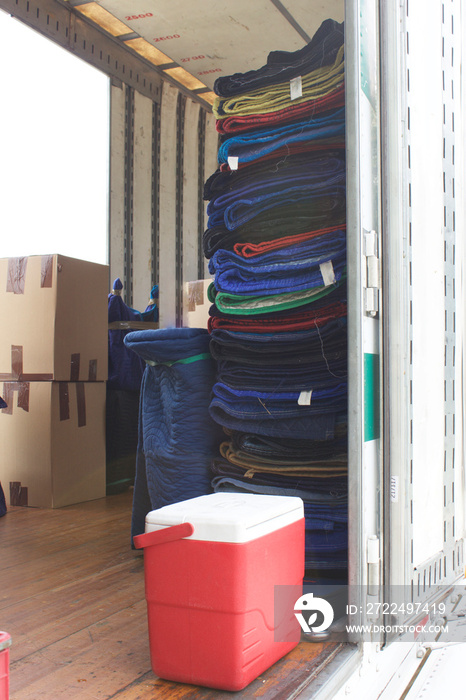 Moving and storage trailer with strapped moving blankets and packed boxes on floor