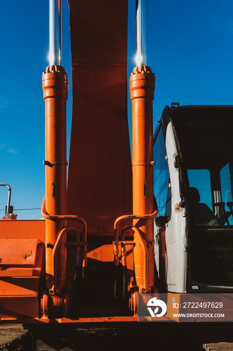 Close up of orange and chrome excavator with blue skies