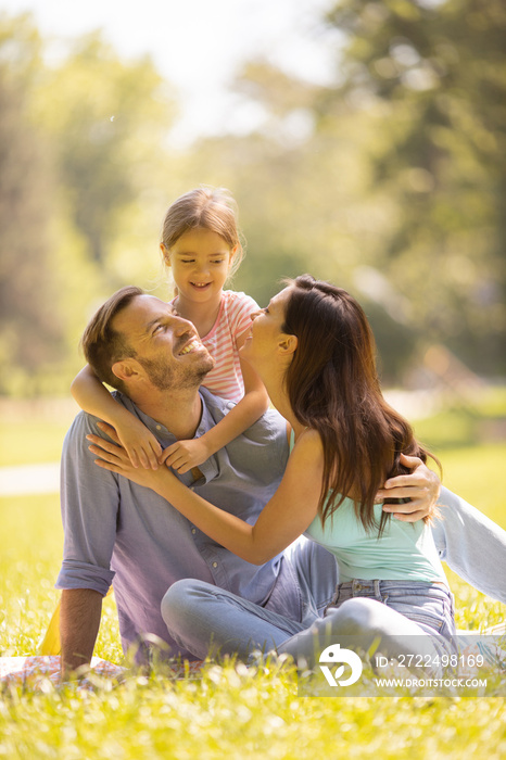 Happy young family with cute little daughter having fun in the park on a sunny day