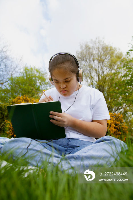 Young mid-sized woman with Down Syndrome listening to music in the park