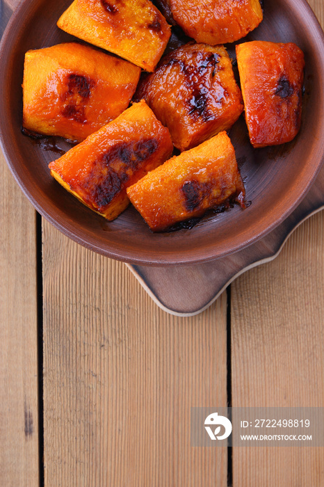 Pumpkin, baked in the oven pumpkin on a wooden background, cooked vegetables in a clay dish in retro style, natural background, vegetarian dish, Mexican cuisine, minimalism, copy space