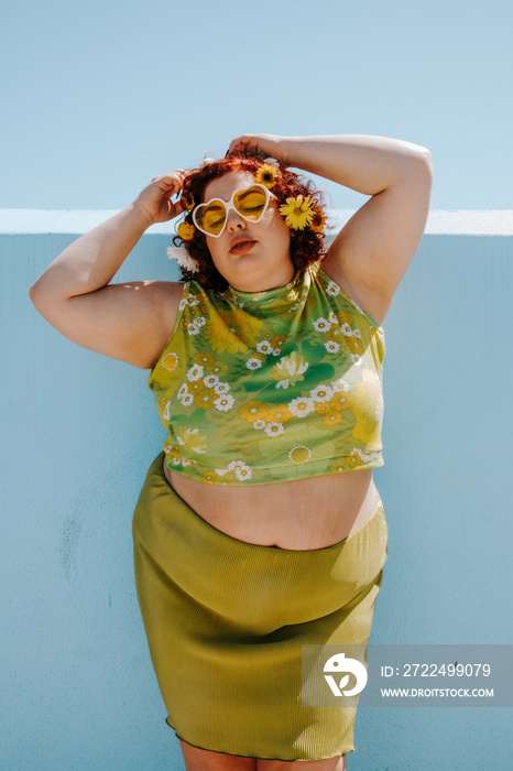 plus size woman with red hair standing against blue wall