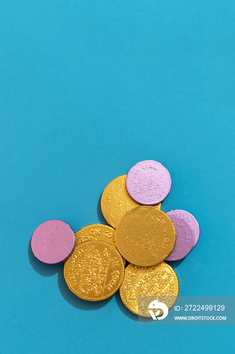 Close up of Hanukkah gelt (money) or chocolate coins, top view on light blue background.