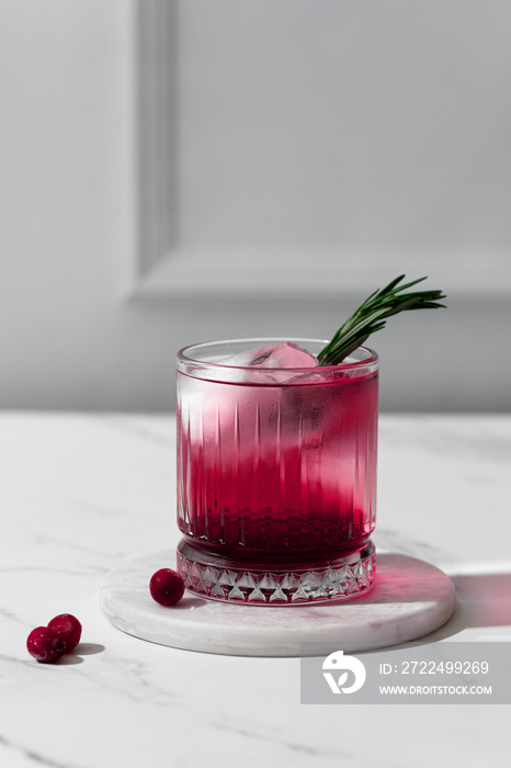 Kir Royal cocktail with cranberries and rosemary in a crystal glass on a white background