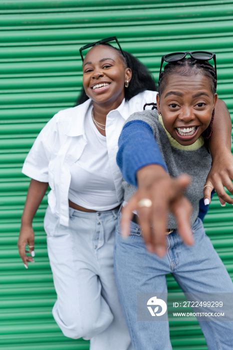 Portrait of stylish female couple against green door