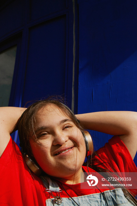 Young curvy woman with Down Syndrome dancing in the sun with headphones