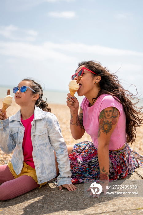 Mother and daughter (8-9) eating ice cream on beach