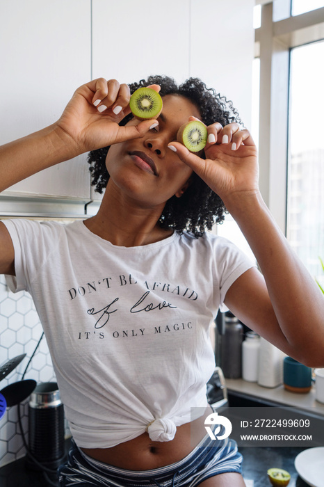 Beautiful black woman with curly hair holding kiwis in her hands