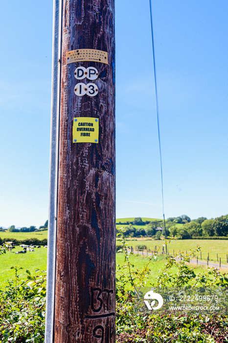 Sign on a wooden telephone pole warning people that the pole is carrying fibre optic cable.