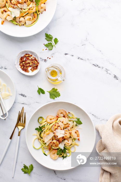 Shrimp and zucchini noodles or zoodles pasta with parmesan and chili flakes plated in white pasta bowls