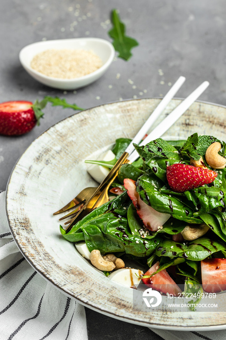 Fresh vegetarian salad with kale, strawberry, spinach leaves and feta cheese. vertical image. top view