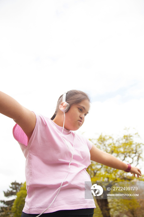 Young mid-sized woman with Down syndrome dancing outdoors