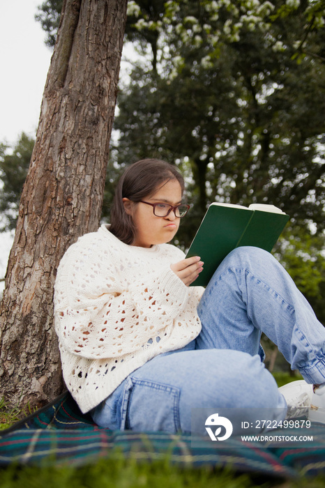 Curvy woman with Down syndrome reading in the park