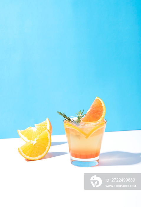 Cold and refreshing orange punch cocktail with orange slice on blue background. summer drink.