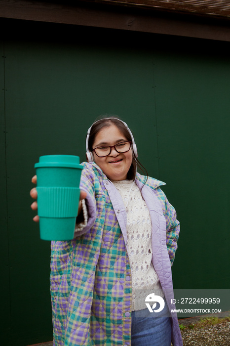 Young mid-sized woman with Down Syndrome holding a reusable coffee cup