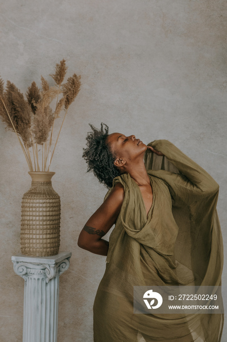 African American Canadian woman dancing chin up next to roman column