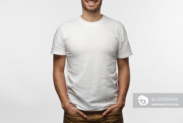 Young european man standing with hands in pockets, wearing blank white tshirt with copy space for yo