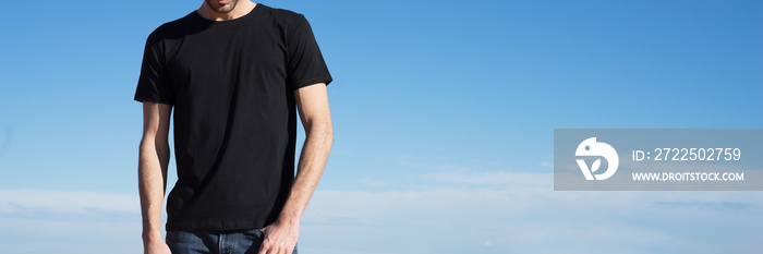 Photo of a man wearing black t-shirt. Blue sky on background