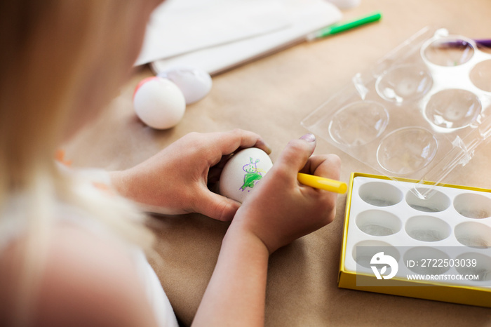 High angle view of girl drawing on Easter egg on table