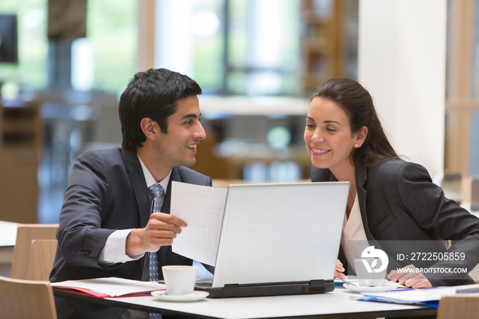 Business people discussing paperwork at laptop