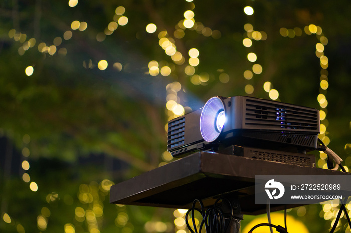 Black Projector on stand table ready for presentation in yellow bokeh background