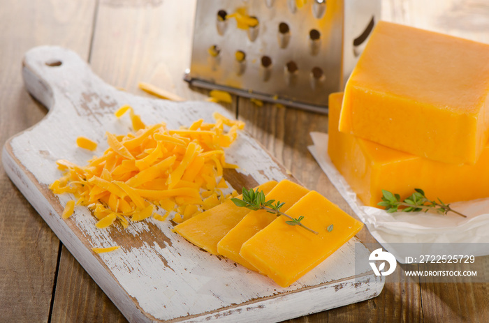 Grated Cheddar Cheese on  a wooden Board.