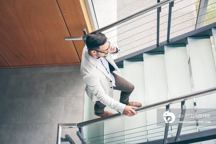 Business man walking to work. Business man on stairs talking on smart phone.