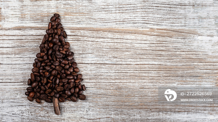 Shape of Christmas tree made of coffee beans, anise star and cinnamon sticks, on wooden table. Winte