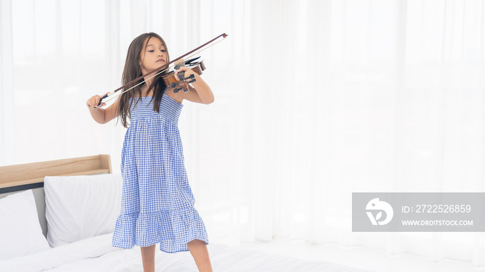 Happy Asian Girl are playing violin in the white room.