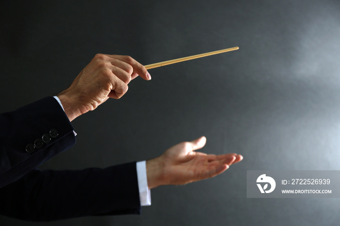 Music conductor hands with baton on black background