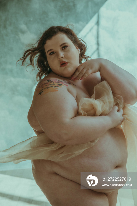 plus size caucasian woman holding white fabric to body