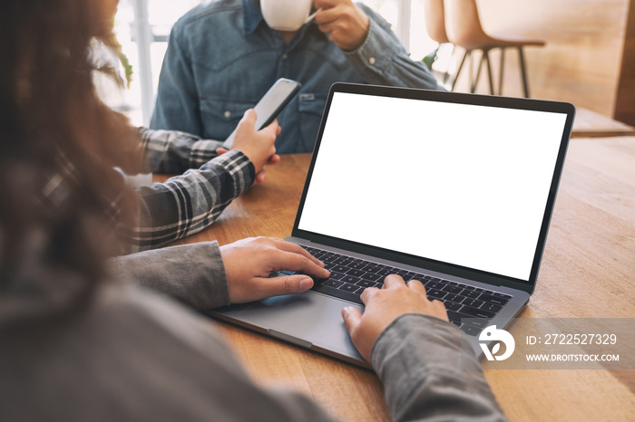 A woman using and typing at mockup laptop computer with friends in background