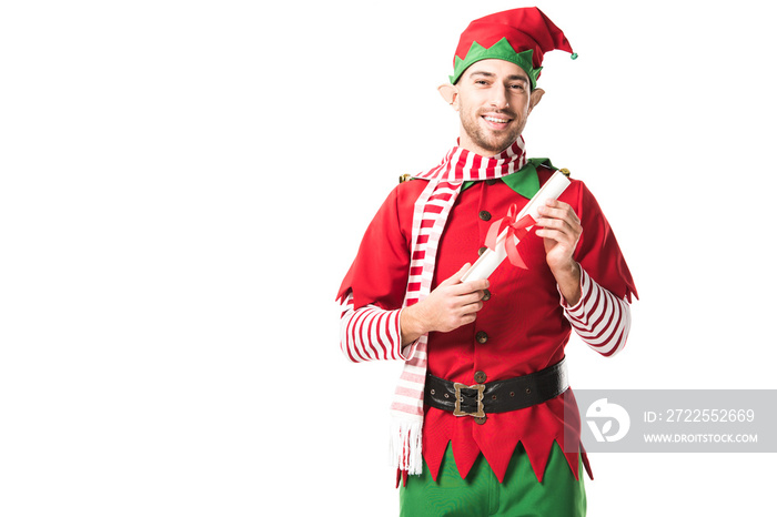 smiling man in christmas elf costume holding wishlist roll isolated on white