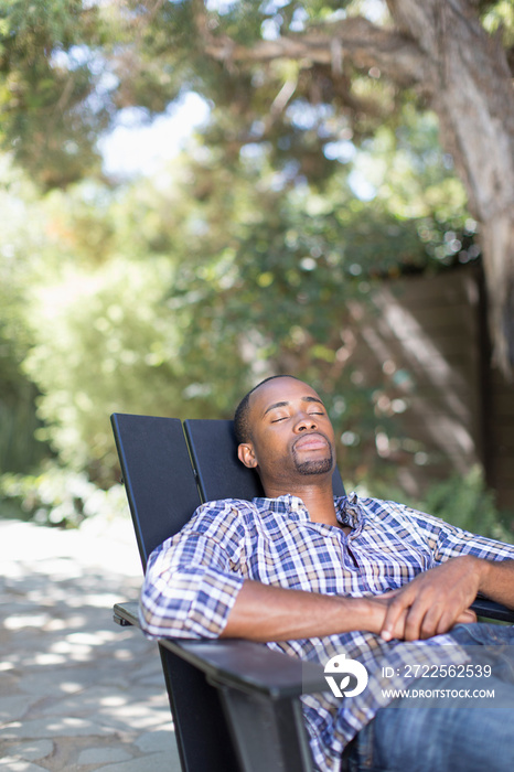 Serene young man relaxing in chair on patio