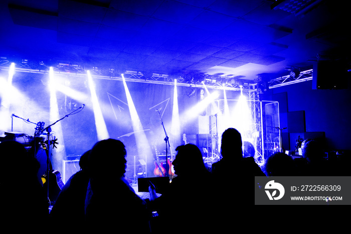 明亮的舞台灯光前音乐会人群的剪影，有乐队和人的小酒吧