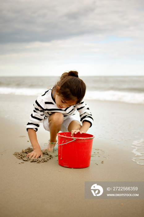 Girl playing with sand on beach