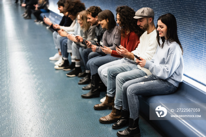 Young multiracial friends having fun using mobile phones inside subway station - Focus on right woma