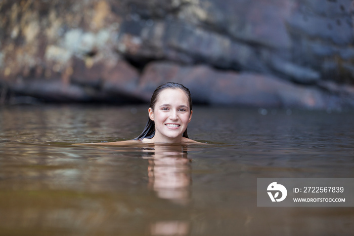 Portrait smiling young woman swimming in lake