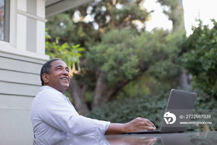 Smiling senior man using laptop on patio