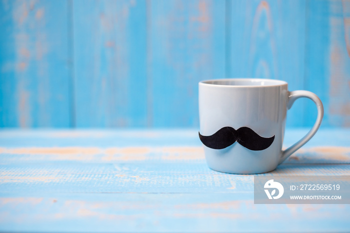 Blue coffee cup with Black mustache on wood table background in the morning. Father, International m